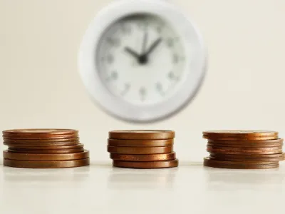 stacks of pennies in front of a clock