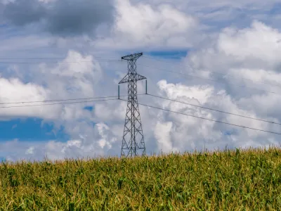 a power line tower cares power lines over a corn field in Minnesota