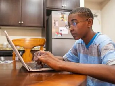child on laptop at kitchen table