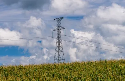 a power line tower cares power lines over a corn field in Minnesota