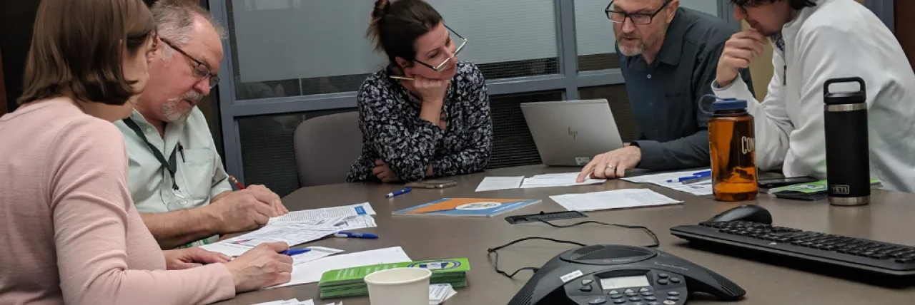 a group of individuals review energy bills at a conference room table