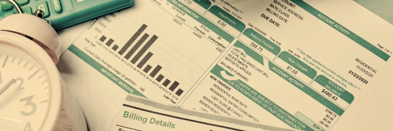 energy bills, covered by a clock, lightbulb, and calculator