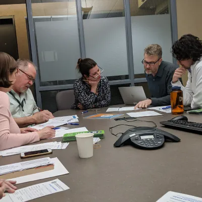 a group of individuals review energy bills at a conference room table