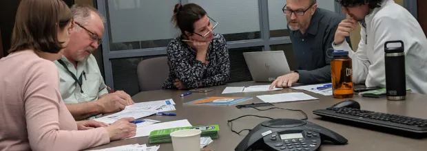 a group of individuals review energy bills at a conference room table
